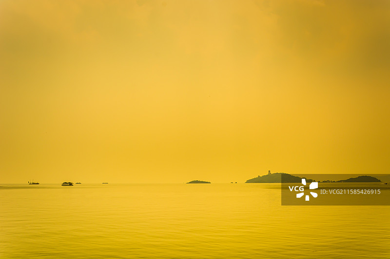 金色薄雾笼罩平静海面与远处岛屿图片素材