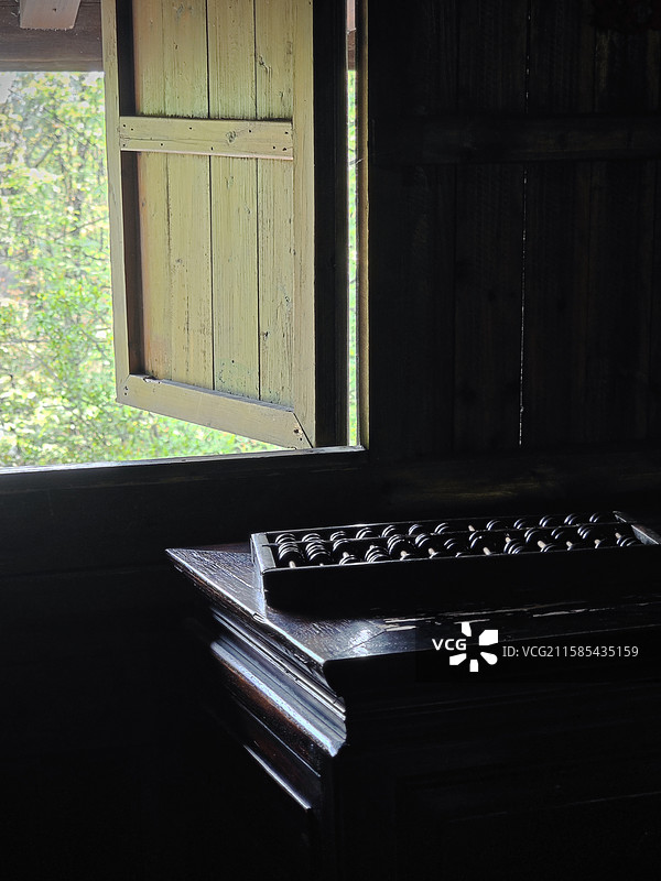 木桌上的算盘，家里靠木窗边的木桌子，老房子里怀旧的木质家居家具，杭州西溪湿地烟水渔庄里的西溪人家室内图片素材