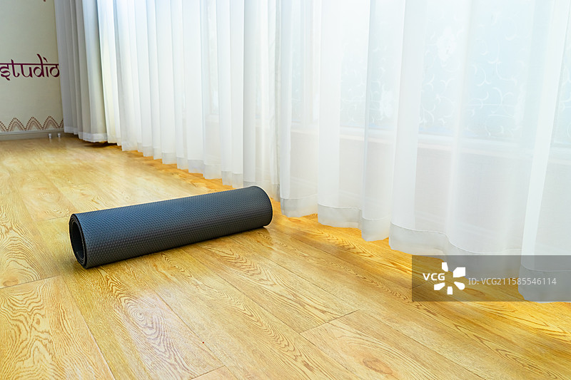 中国室内的瑜伽馆，木地板上的放置的黑色的展开的圆柱形瑜伽垫，室内无人图像摄影图片素材