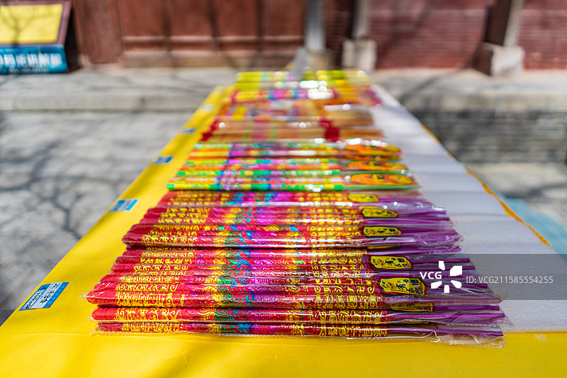 中国宗教用品拍摄主题，桌子上摆放着多样的彩色的带包装正在待售的香火，户外白昼无人图像摄影图片素材