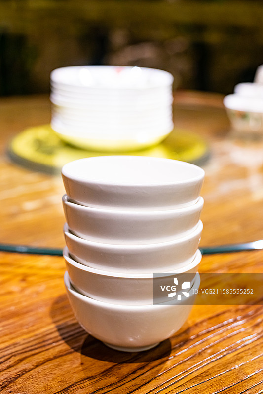 中国餐饮餐厅饭店饭馆行业，空的餐桌拍摄主题，中国传统木制圆桌上的叠起来的茶碗餐具，室内无人图像摄影图片素材