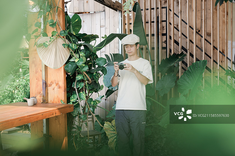 在绿植主题咖啡馆拿着相机的男性图片素材