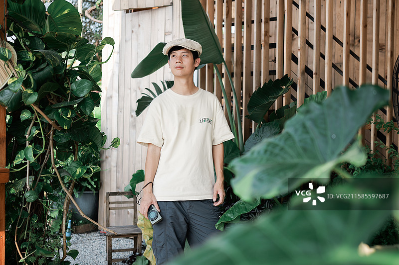 在绿植主题咖啡馆拿着相机的男性图片素材