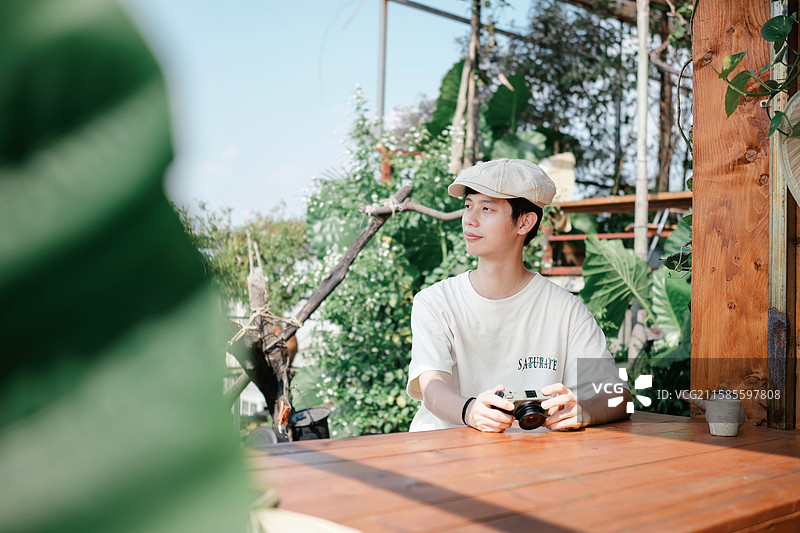 在绿植主题咖啡馆拿着相机的男性图片素材