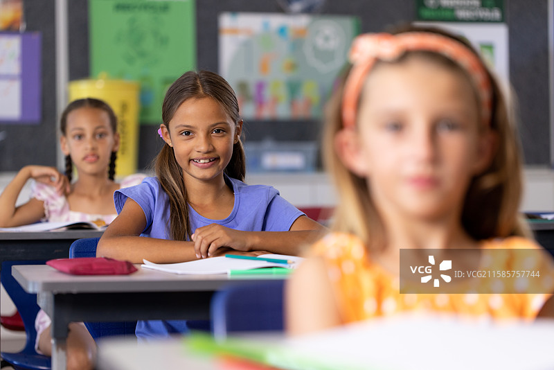 三个女孩坐在学校教室的桌子旁图片素材