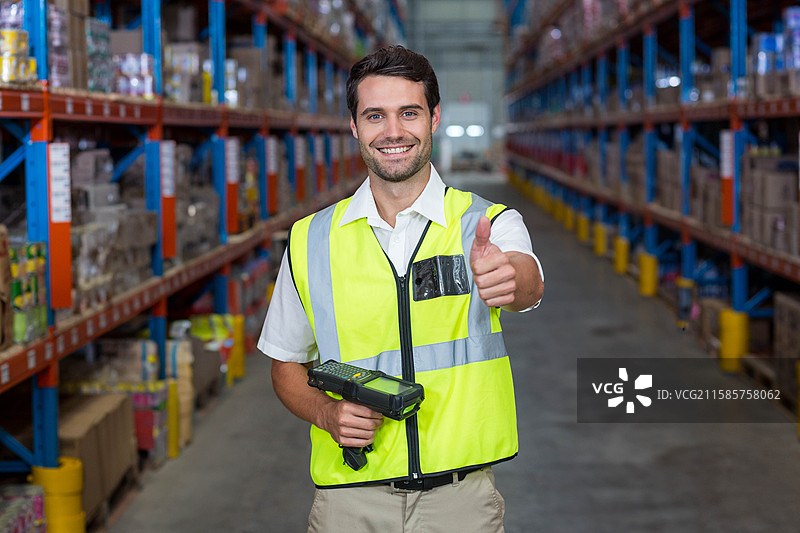 仓库工人穿着安全背心，在货架过道中使用条形码扫描器扫描箱子图片素材