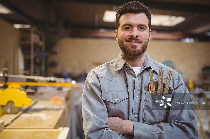 带有黄色安全护罩的台锯静置在工作台上，工作灯下，留有空白空间。图片素材