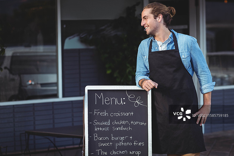 咖啡馆人行道上，黑板菜单展示新鲜的可颂和三明治，旁边有桌椅。图片素材