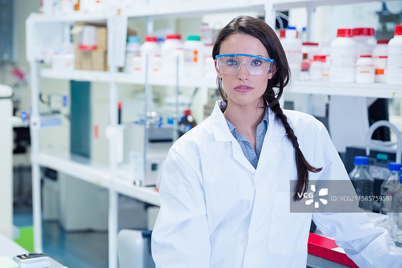 实验室中，白色工作台上放着带有红色、绿色和蓝色瓶盖的试剂瓶，旁边有玻璃器皿。图片素材