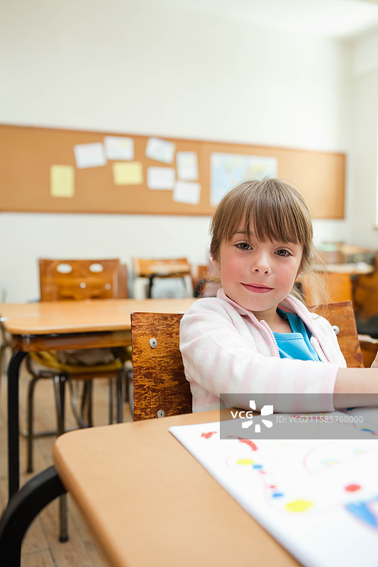 女孩子在学校桌子旁的公告板前绘制五彩缤纷的艺术作品，留有空白空间。图片素材
