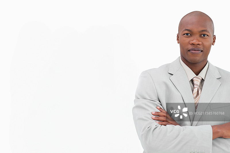 穿着灰色西装、条纹领带的非裔美国男性双臂交叉站在摄影棚中，留有空白空间。图片素材