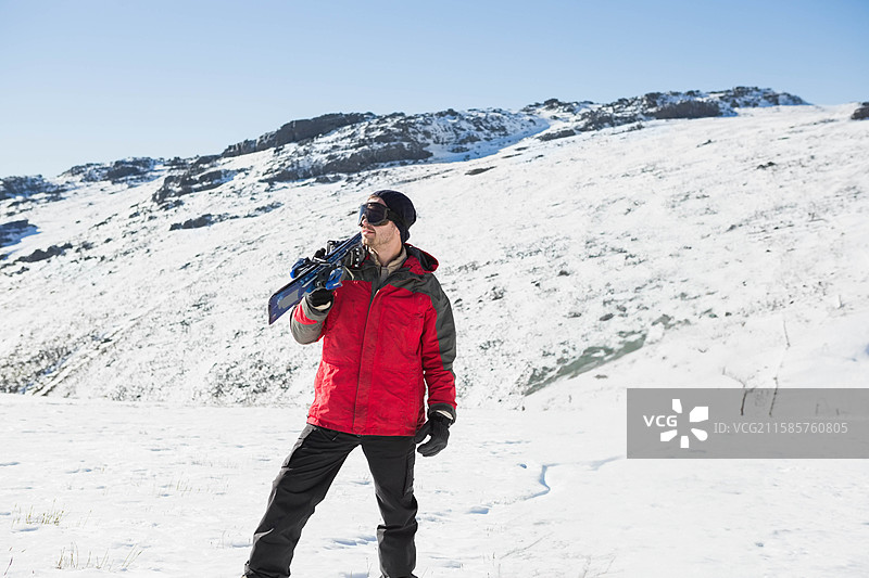 一对滑雪板和滑雪杖靠在雪覆盖的山顶上，映衬着淡蓝色的天空。图片素材
