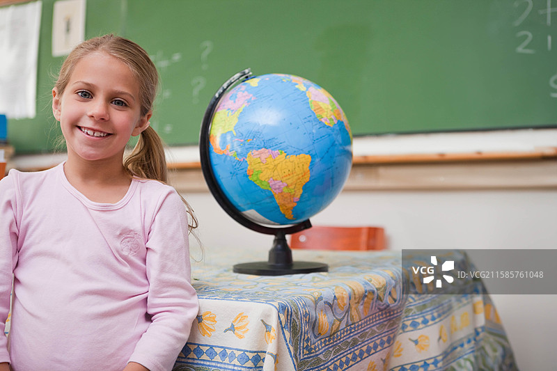 靠在图案桌布上的女学生，身旁是黑板和世界地球仪，留有空白空间图片素材