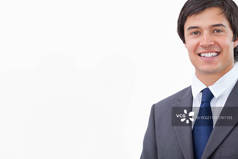 男士微笑，穿着深灰色西装，白色衬衫和蓝色领带，置身于摄影棚，留有空白空间。图片素材
