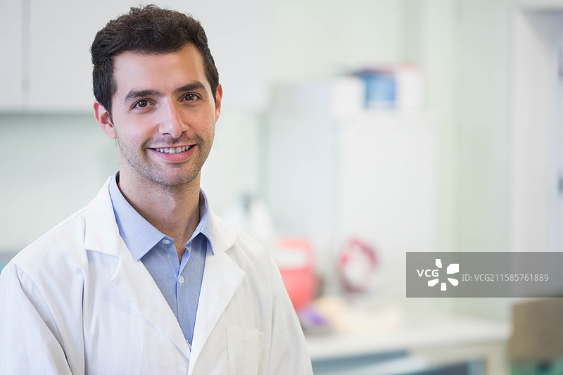 穿着白色实验室外套的男性研究员站在配有锐器容器的研究实验室中图片素材
