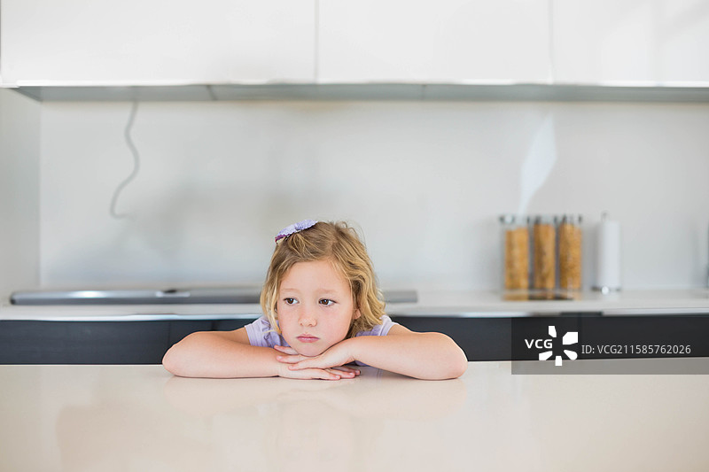 女孩靠在厨房的石英台面上，查看炉灶旁的谷物罐。图片素材