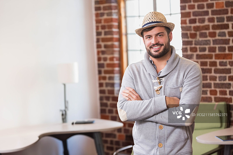 戴着草编礼帽的非裔美国男性站在办公室里，身后是桌子和砖墙，留有空白空间。图片素材