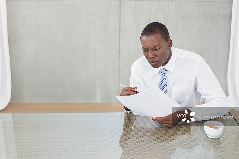 身穿西装的非裔美国男性在会议桌前写文件，旁边有咖啡杯，留有空白空间图片素材
