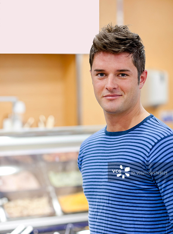 男子站在自助餐台前，玻璃防护罩、金属托盘和餐具，留白空间图片素材