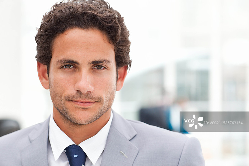 身穿灰色西装和图案领带的商务专业人士站在明亮的现代办公室里图片素材