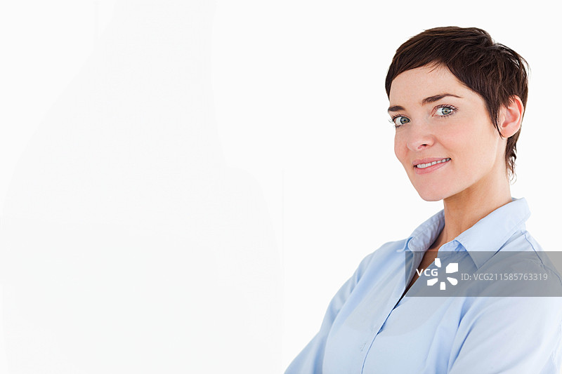 中年女性在工作室中双臂交叉，穿着浅蓝色衬衫，留有空白空间。图片素材