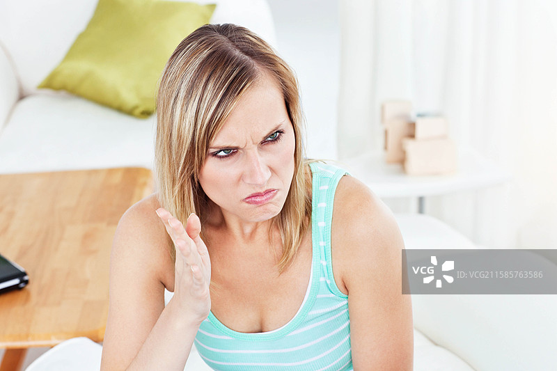 浅绿色的枕头放在白色沙发上，黑色的笔记本电脑合上放在木桌上，留有空白空间。图片素材