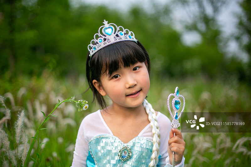 小女孩身着公主装，手持权杖在草地上图片素材