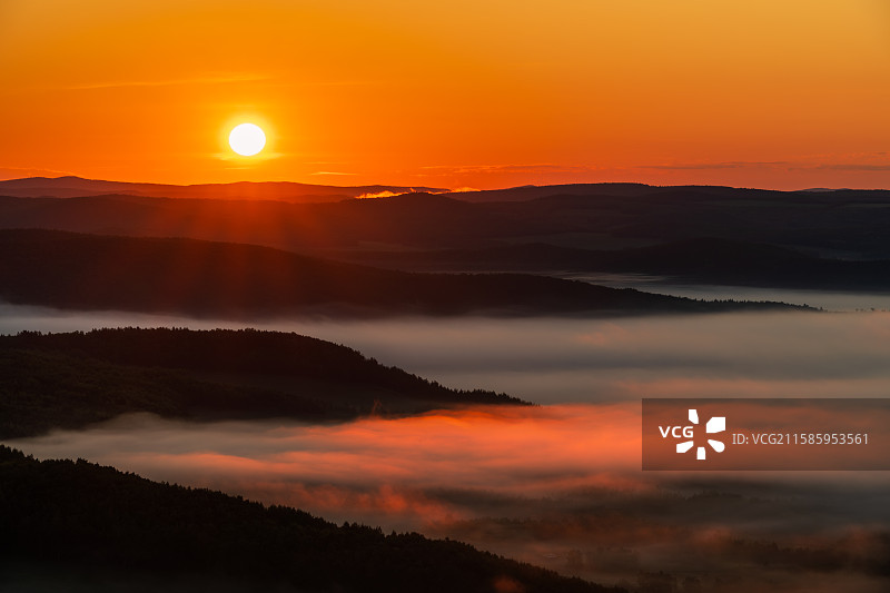 夏末秋初清晨的大兴安岭加格达奇，太阳从起伏群山上升起，晨雾笼罩绿色森林，被阳光照亮图片素材