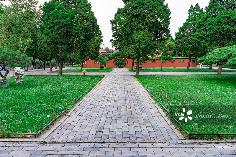中国山东泰安著名景点泰山旅行旅游目的地，泰山第一行宫岱庙，素景中式庭院里的月亮门和花坛，户外白昼无人图片素材