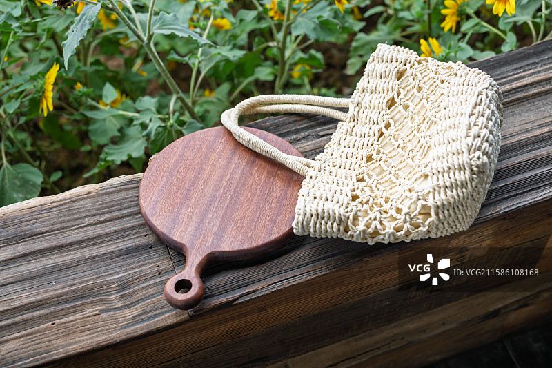 编织包与木制砧板静置于花园木凳上图片素材