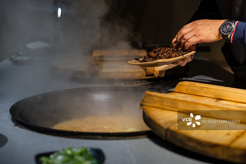 厨师正在将炒好的食材放入热锅中图片素材