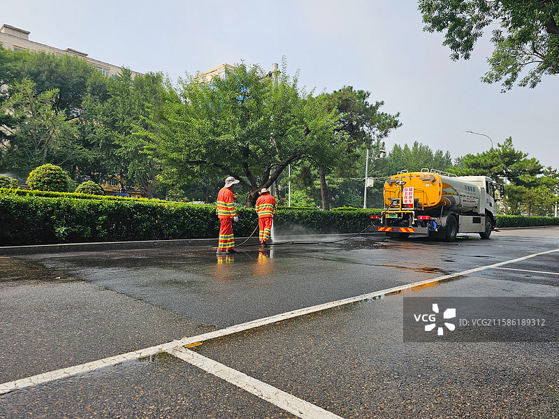 撒水车和环卫工正在道路上撒水清理卫生图片素材