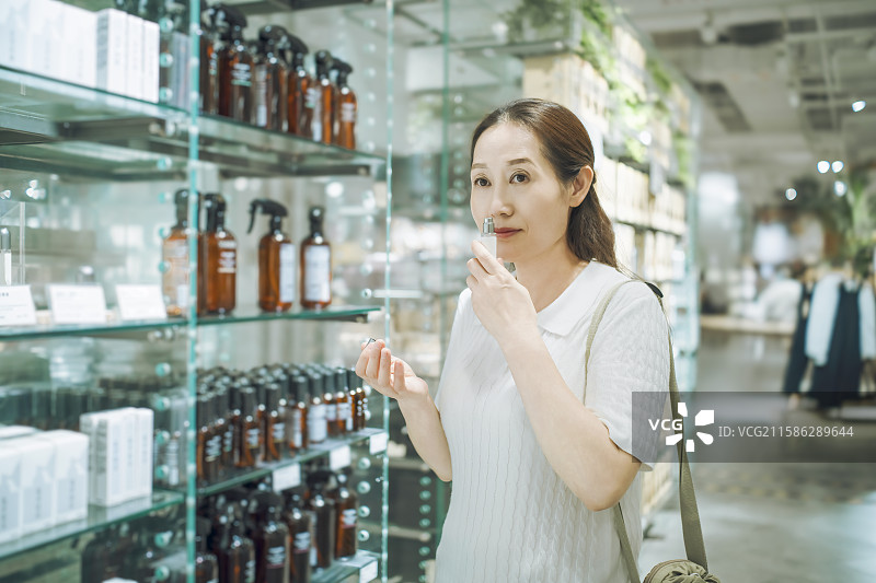亚洲女性在美妆店闻香水图片素材