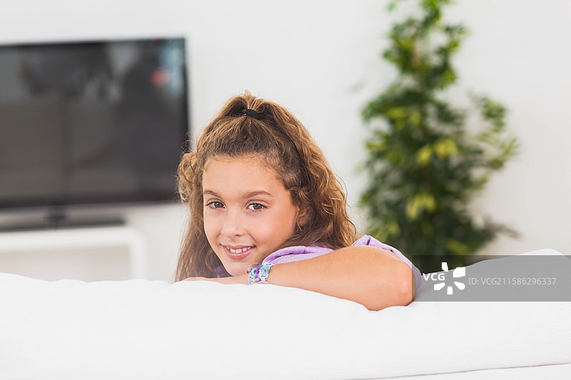 明亮的客厅里摆放着白色沙发，配有平面电视和高大的盆栽植物。图片素材