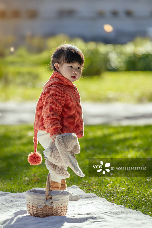 日光下站在博物馆树草坪垫上手拿乖乖兔的可爱小女孩图片素材