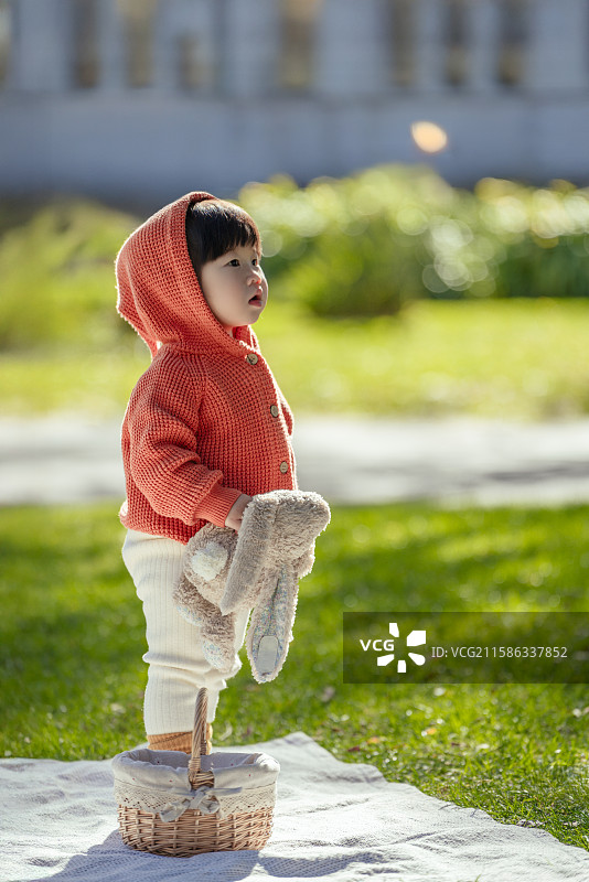日光下站在博物馆树草坪垫上手拿乖乖兔的可爱小女孩图片素材