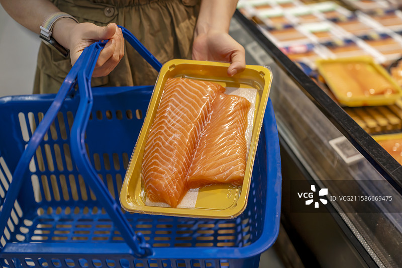 超市中手持三文鱼的人图片素材