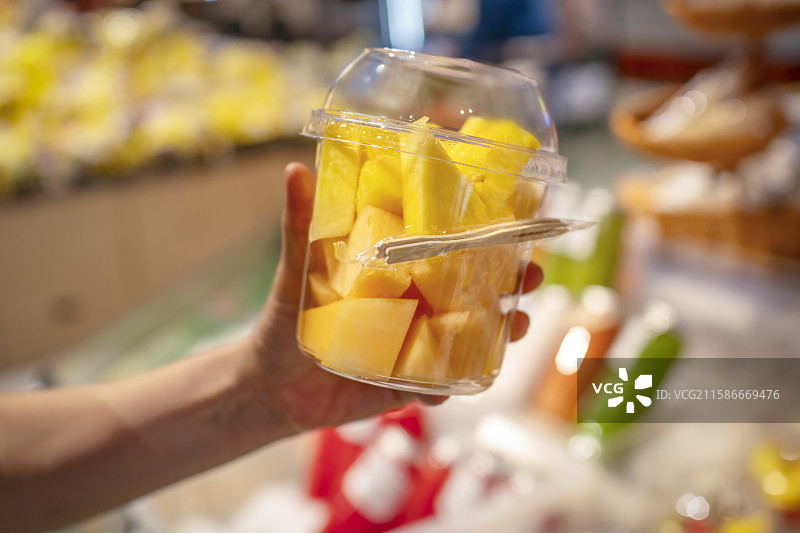 手拿着装有切片水果的塑料盒图片素材