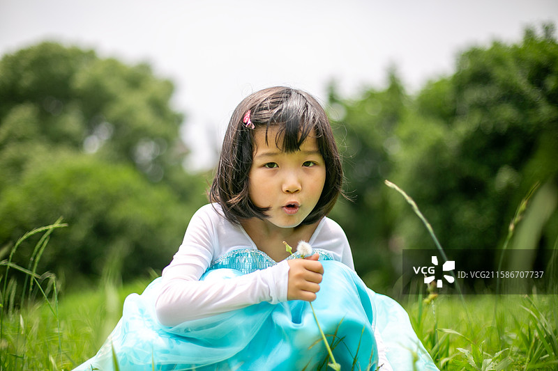 可爱的女孩在户外吹蒲公英图片素材