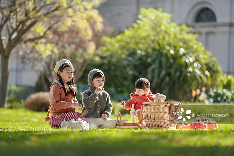 博物馆前花园草坪上野餐的三个小孩图片素材