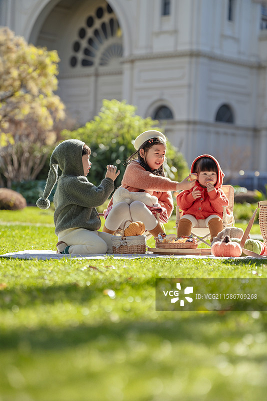 博物馆前花园草坪上野餐的三个小孩图片素材