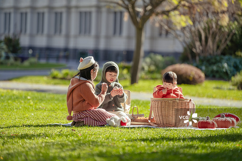 博物馆前花园草坪上野餐的三个小孩图片素材