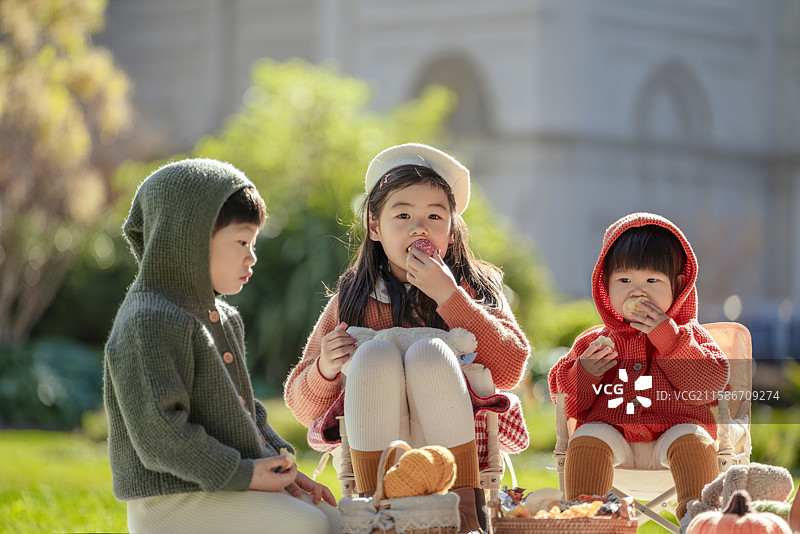 博物馆前花园草坪上野餐的三个小孩图片素材