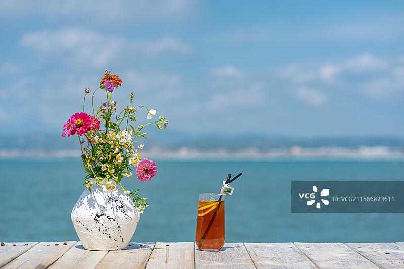 盛夏海边木桌上的花瓶与柠檬饮料图片素材