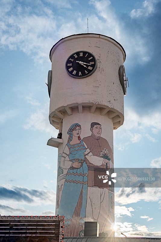 室韦临江屯水塔上，传统服饰人物壁画映衬蓝天白云，古朴大钟显典雅。图片素材
