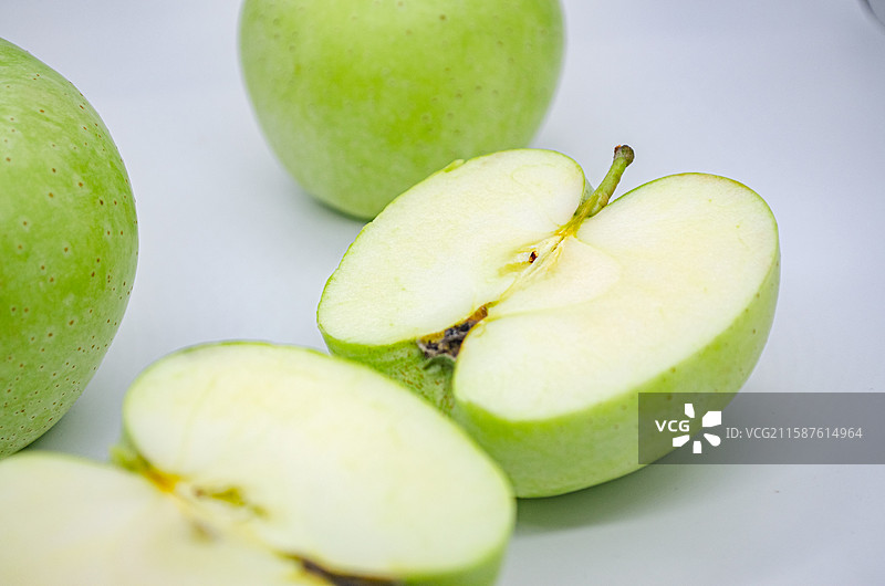 中国传统水果美食饮食产业影棚拍摄主题，白色背景下切开的翠绿色黄色的青苹果，室内无人图像摄影图片素材