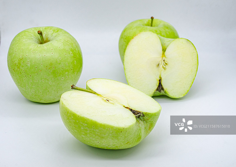 中国传统水果美食饮食产业影棚拍摄主题，白色背景下切开的翠绿色黄色的青苹果，室内无人图像摄影图片素材