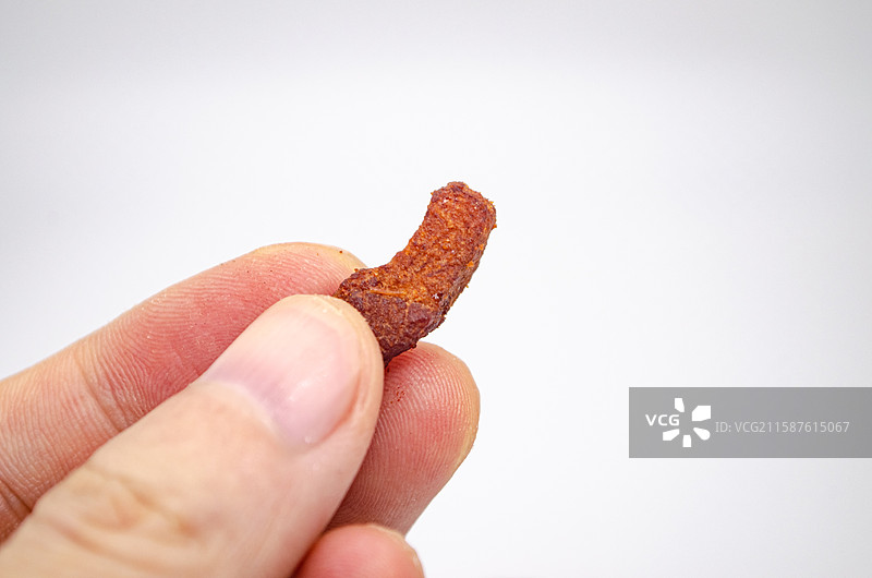 中国传统美食饮食产业影棚拍摄主题，一只手拿着炸猪油后的金黄色的油炸油炸脆哨，室内无人图像摄影图片素材