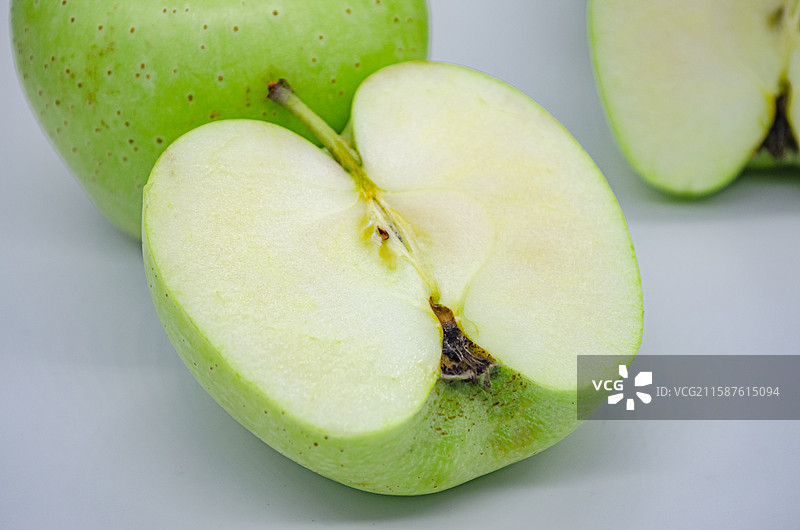 中国传统水果美食饮食产业影棚拍摄主题，白色背景下切开的翠绿色黄色的青苹果，室内无人图像摄影图片素材