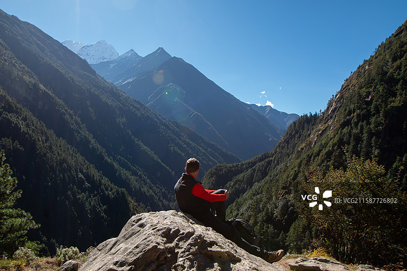 坐在岩石上俯瞰山谷的人，尼泊尔EBC徒步图片素材